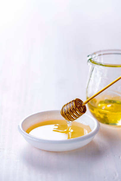 istock Honey with honey dipper on white table. 1442218292
