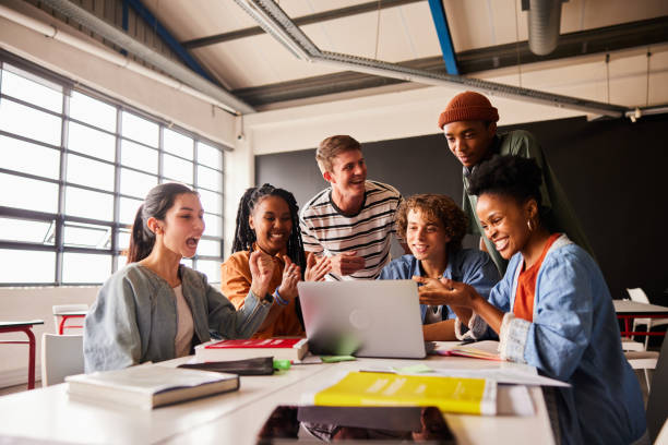 istock Students cheering at something streaming on a laptop in a classroom 1442222794