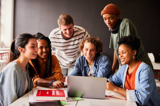 istock Smiling students watching something on a laptop in a classroom 1442226775