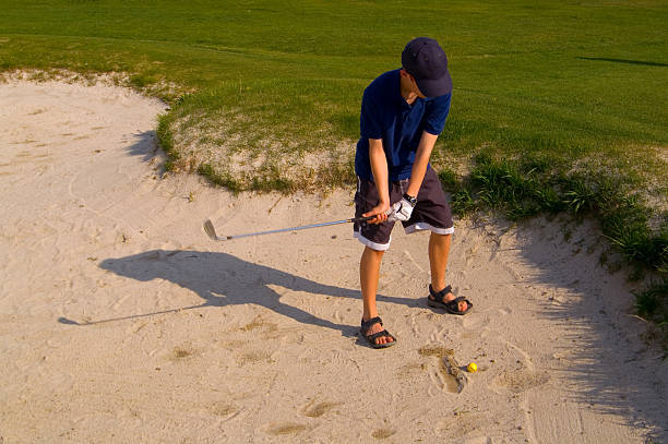 Young Teenage Boy Golfing in Sand Trap stock photo