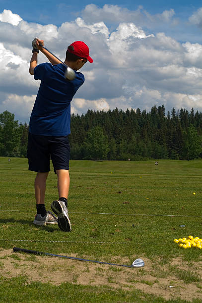Young Teenage Boy Golfing at Driving Range stock photo