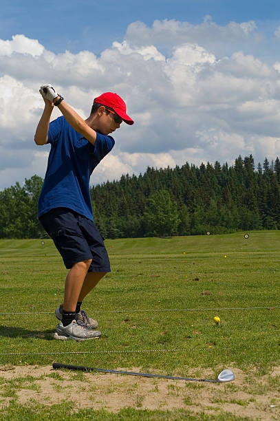 Young Teenage Boy Golfing at Driving Range stock photo