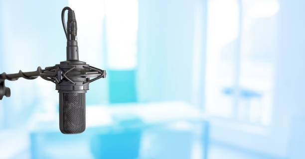 istock Podcast background. Recording studio microphone and blue office background with copy space.. Media workplace for broadcast or journalism banner 1442231142