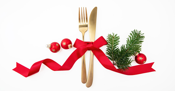 Christmas holiday celebration dinner. New Year table setting isolated on white. Golden cutlery, Xmas decoration and red ribbon top view.