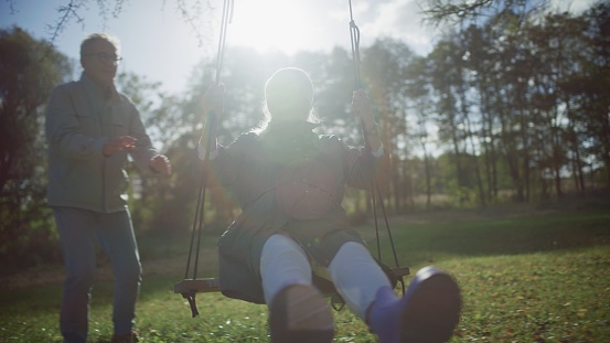 Two active seniors out on a date together. Husband pushing wife on a swing. A life of love spent together