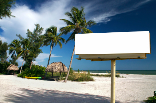 Tropical beach setting with a place to eat - included is a white billboard for you to place text or an advertisement - maybe for a travel ad?