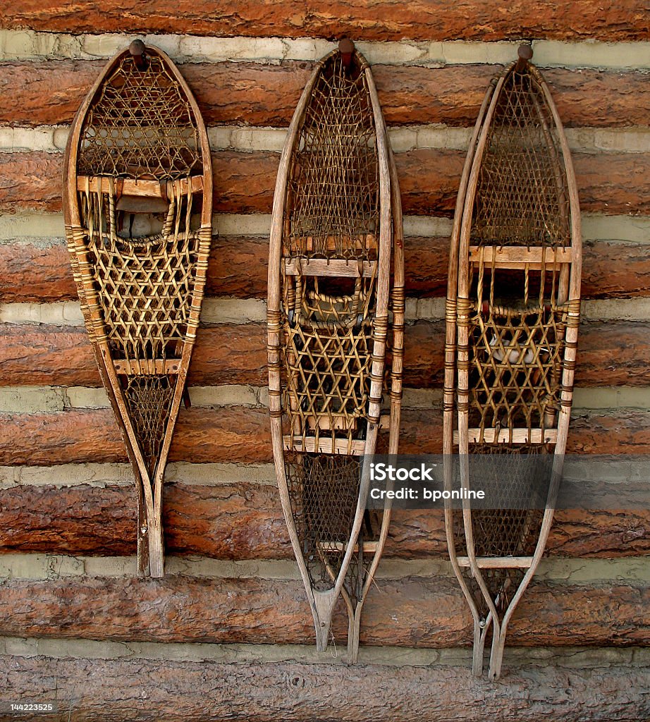 Wood and string snowshoes hanging on pegs Three sets of snowshoes hanging on a wall. Adventure Stock Photo