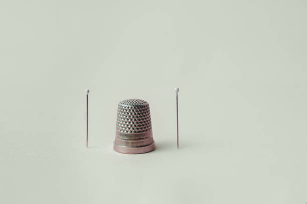 istock A grey thimble and two pearl head needles on a pastel color background. 1442236666