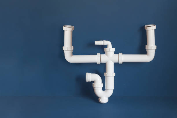 An isolated assembled double adjustable sink siphon for a 2-bowl sink with a horizontal outlet on a colorful blue studio background with copy space