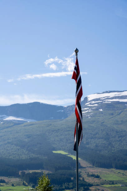 istock the norwegian flag hangs on a flagpole in the shadow, with a mountain landscape behind it 1442238415