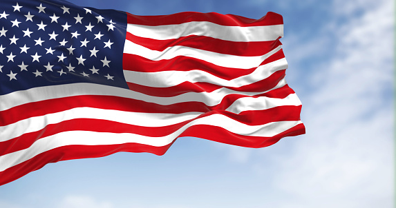 The national flag of the United States of America waving in the wind on a clear day. Patriotism concept. 3D illustration