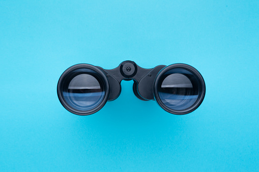 Binoculars isolated on blue background. Front view.
