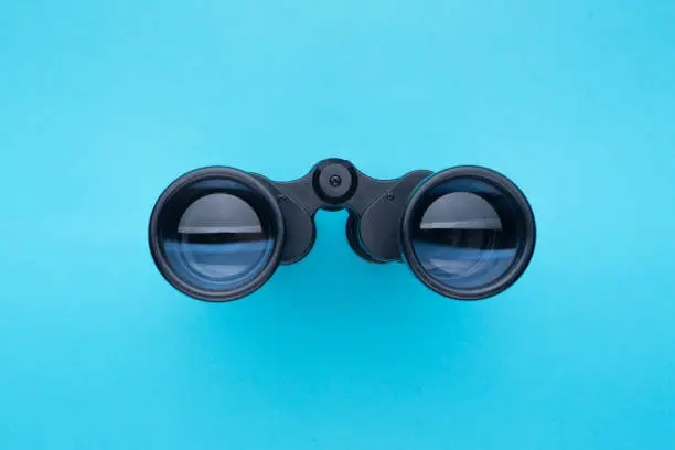 Binoculars isolated on blue background.