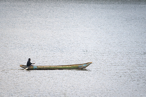 Kabale, Uganda - June 12, 2022: Man in a dugout canoe on Lake Bunyonyi (Uganda), sunny day in summer