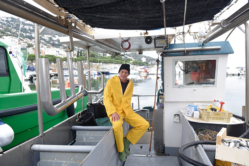 portrait of a fisherman sitting in his boat and looking a camera