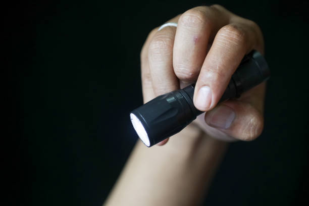 istock Close-up of a person's hand holding a flashlight on a black background. Close up view. 1442247507