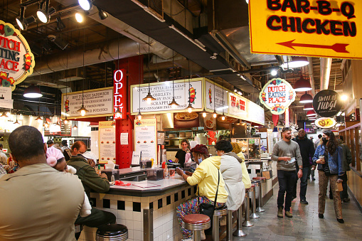 Philadelphis, Pennsylvania, USA - 29 April 2022:People sitting at a luch counter eating a meal at Reding Market Terminal with some wearing masks in April 2022.