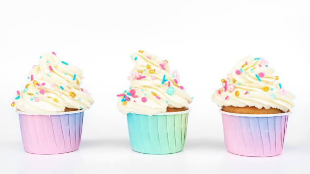 istock Vanilla cupcakes set in gradient paper cups. Cute cupcakes with buttercream, decorated with colorful sprinkles on a white background. Festive treat at children's and wedding parties. 1442247965