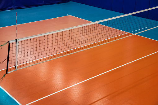 Volleyball court with net in old school gym, top view, copy space. Backdrop sports image of volleyball courts in sport hall. Concept of team game, active match, healthy lifestyle and team success