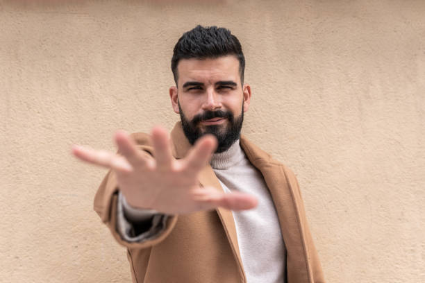 istock Bearded young man in turtleneck holding out his hand while making a half-smile gesture. 1442250721
