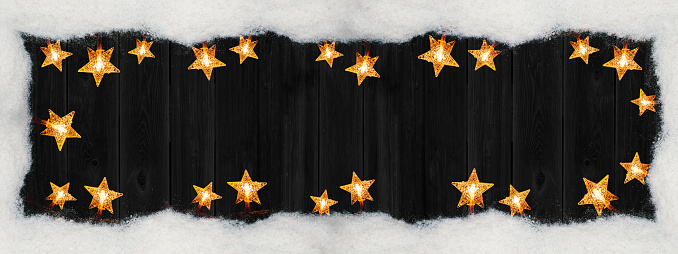 Chrsitmas celebration decoration background banner panorama - Frame made of snow and golden star light chain on dark black wooden boards wall texture