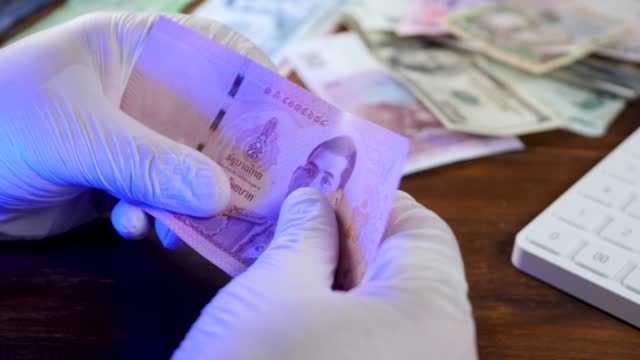 Inspection of detail and lit up security strip thai baht banknote