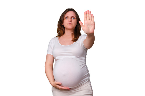 Stop gesture with hand forward in pregnant woman, studio shot on white background
