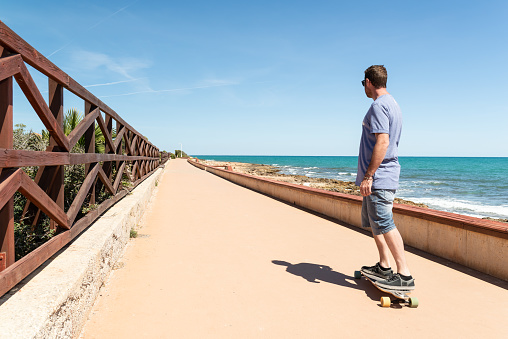 Man longboarding on a skate lane near Mediterranean sea.
