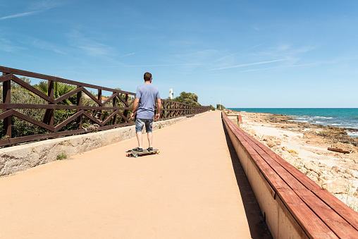 Man having a fun day with his longboard at the mediterranean coast.