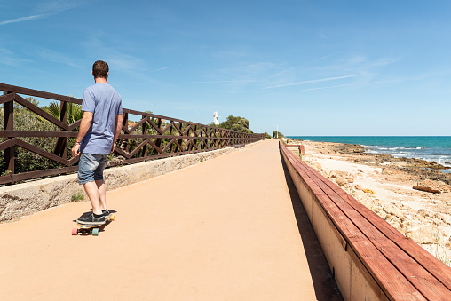 Young man learning longboarding close to the beach.