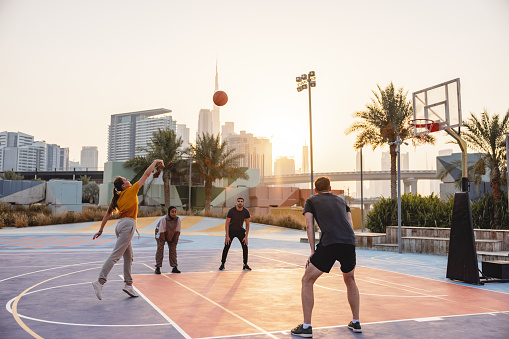 Caucasian Female Basketball Player Doing A Pull-Up Jump Shoot Toward The Basket. Group Of Friends Having Fun Playing Street Basketball In Dubai.