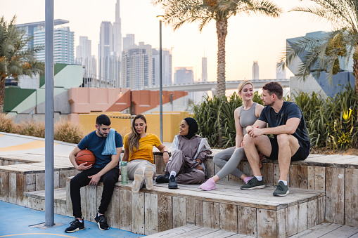 Multi Ethnic Young Adults Sitting Outdoors After A Basketball Game At A Basketball Court In Dubai.