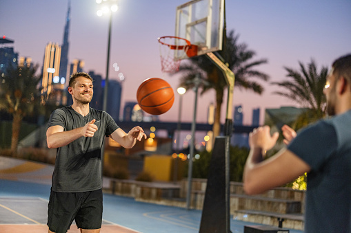 Two Amateur Male Friends Passing The Ball Outdoors At Evening In Dubai.