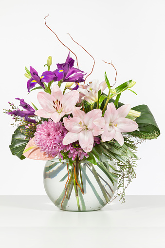 Elegant flower arrangement in beautiful vase isolated in a bright white studio portrait interior
