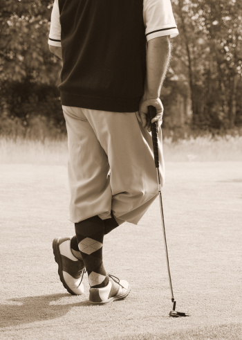 Golfer in old-style argyle socks, saddle golf shoes, and knicker pants. Duotone to enhance antiquity.