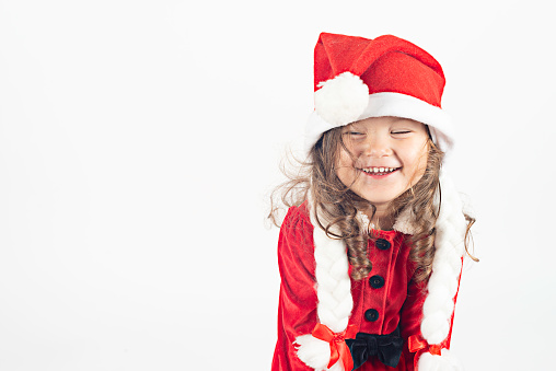 Little girl in santa costume with a toothy smile in front of white background