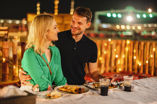 Young adult Caucasian tourists having a romantic dinner a safari camp at night in Dubai.