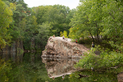 Two girls on top of a large granite rock at the edge of an old granite quarry pond.