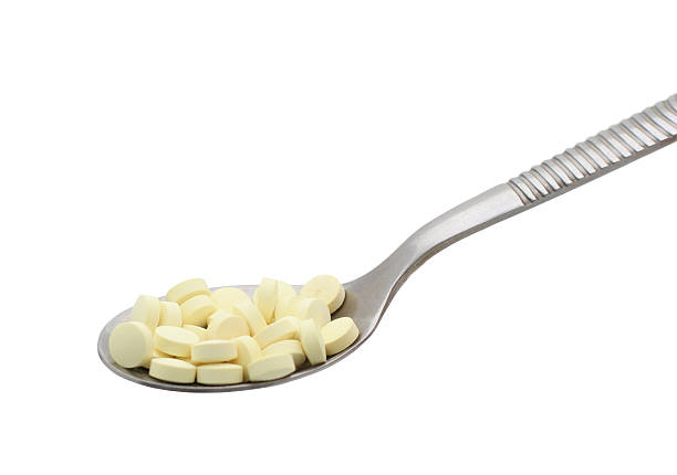 Spoon full of pills isolated stock photo