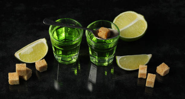 Green absinthe drink with lime and sugar Green absinthe drink with lime and sugar on black background absinthe spoon stock pictures, royalty-free photos & images