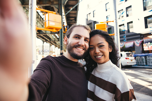 Millennial couple in the streets of Bushwick - Brooklyn and take a funny selfie.