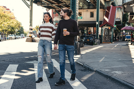 Millennial couple walking on the sidewalk in Brooklyn - New York.