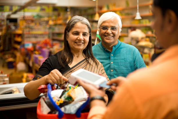 senior couple paying through credit card to owner - asian ethnicity shopping mall supermarket store imagens e fotografias de stock