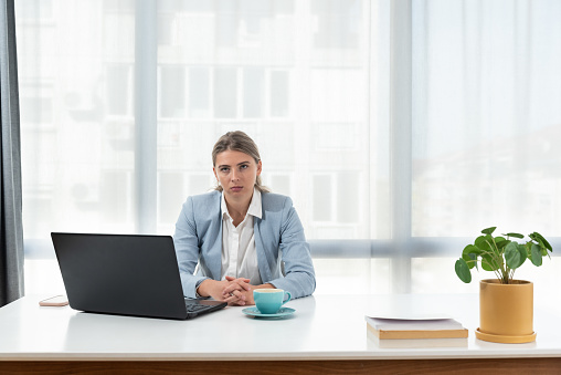 Frustrated and angry freelancer businesswoman talking on video call, woman arguing and looking at laptop screen, online business conference. Female in smart casual wear sitting at office desk