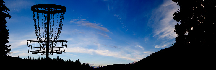 Panoramic shot of a disc golf basket at sunset in British Columbia, Canada.