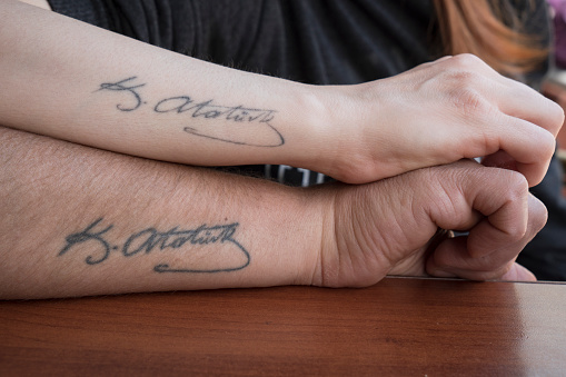 Mustafa Kemal Atatürk tattoo on to a woman's and a man’s arm