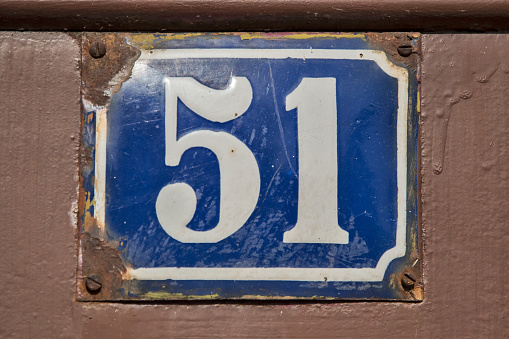 Weathered grunge square metal enameled plate of number of street address with number 51