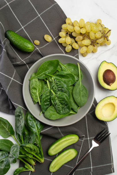 istock Gray culinary background with ingredients for green salad. Spinach with avocado and grapes. 1442276012