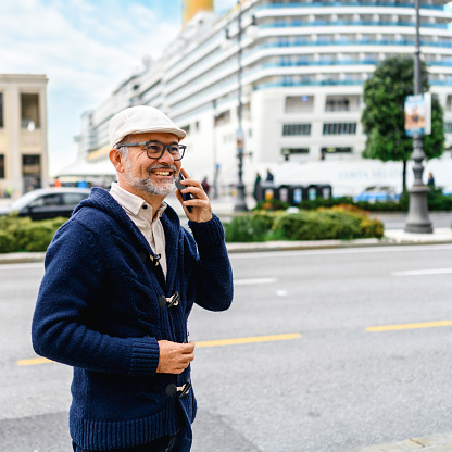 Mature man walking in the city and talking on mobile phone