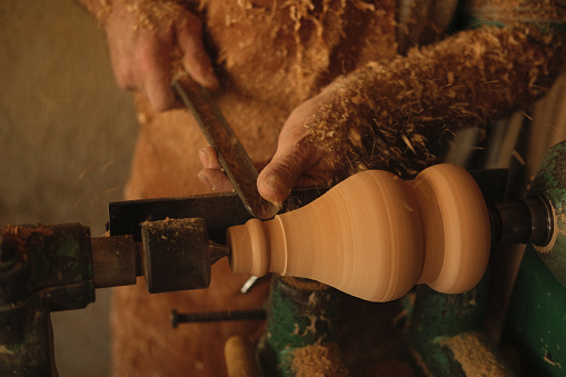 Close-up of a carpenter turning wood on a lathe. Person carving on a lathe